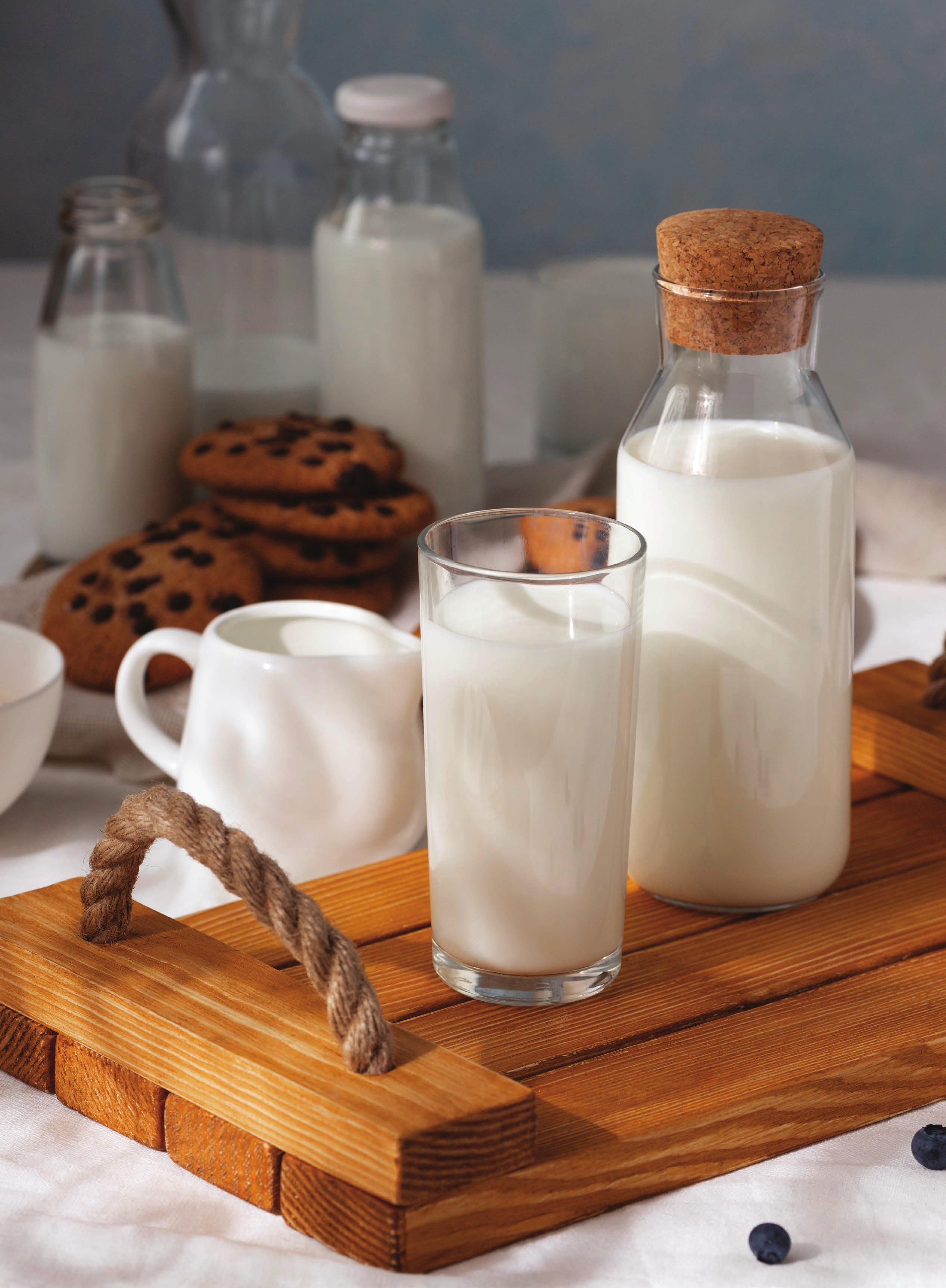 A glass and bottle of Mimas milk on a wooden tray with cookies